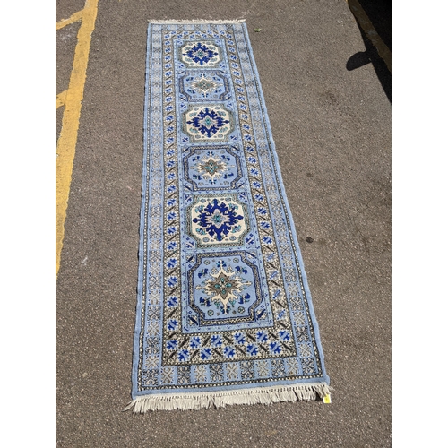 530 - A Moroccan hand woven runner, six central floral medallion, triple guard, on a blue ground with tass... 