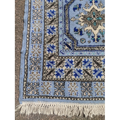 530 - A Moroccan hand woven runner, six central floral medallion, triple guard, on a blue ground with tass... 