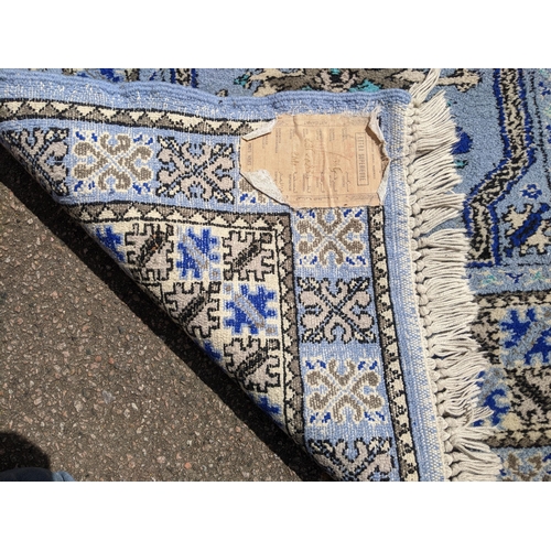 530 - A Moroccan hand woven runner, six central floral medallion, triple guard, on a blue ground with tass... 