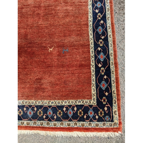 533 - A contemporary Persian hand woven rug having a red ground with triple guard and cream borders, 198 x... 