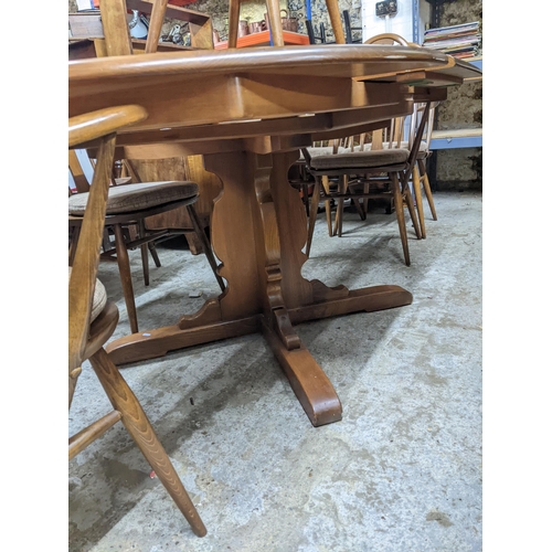 543 - A late 20th century Ercol elm extending dining table with butterfly extending leaf, on pedestal base... 