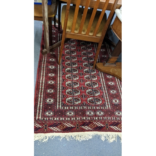 556 - A handwoven Middle Eastern red ground rug with elephant foot motifs and tasselled ends, 130cm x 95cm... 