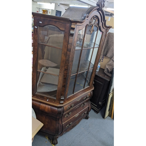 458 - A mid 20th century Dutch walnut veneered bombe display cabinet having a single door above three draw... 