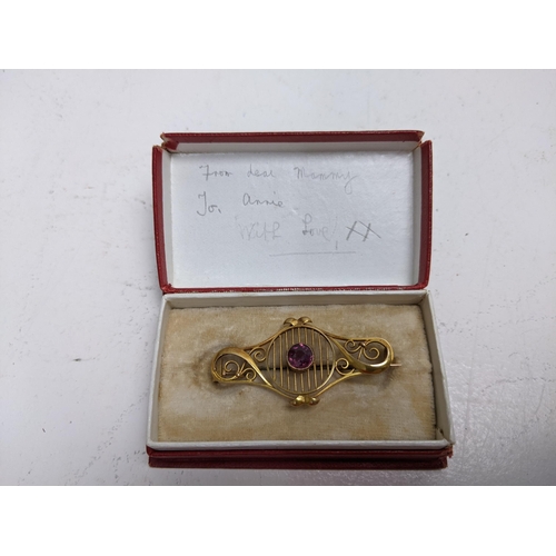 137 - An Edwardian 9ct gold brooch, set with an amethyst and flanked by scrolled ornament, 3.2g total

Loc... 