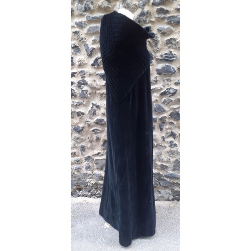 77 - A black velvet full length opera cape having a Gothic style raised collar with a hook and eye and si... 