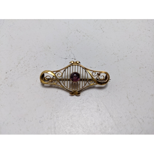 137 - An Edwardian 9ct gold brooch, set with an amethyst and flanked by scrolled ornament, 3.2g total

Loc... 