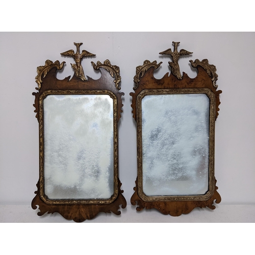 249 - A pair of 20th century Chippendale style parcel-gilt, walnut mirrors surmounted by a bird foliage an... 