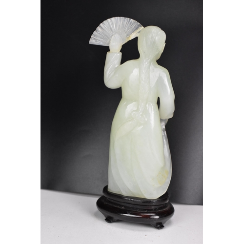 10 - A 20th Chinese jade coloured sculpture of a Geisha figure in a dress, holding a fan aloft in her lef... 