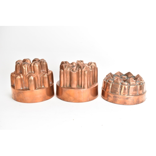 104 - Three 19th century copper jelly moulds, each of castellated form on stepped bases with impressed mar... 