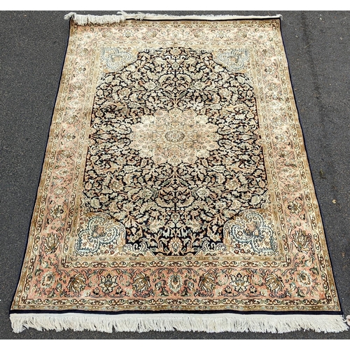 126 - An Indian Kashmir hand woven silk pile rug with a central flower head medallion surrounded by scroll... 