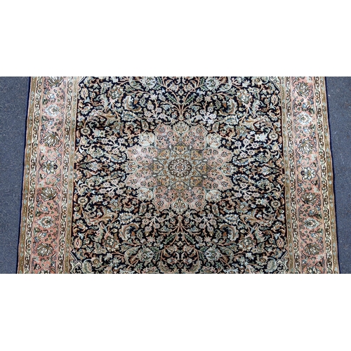 126 - An Indian Kashmir hand woven silk pile rug with a central flower head medallion surrounded by scroll... 