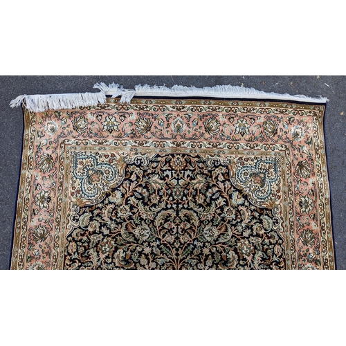 126 - An Indian Kashmir hand woven silk pile rug with a central flower head medallion surrounded by scroll... 