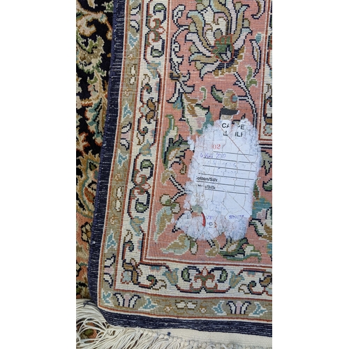 126 - An Indian Kashmir hand woven silk pile rug with a central flower head medallion surrounded by scroll... 