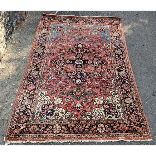 129 - A Persian Sarouk hand woven rug, having a red ground with cenral motif surrounded by vining branches... 