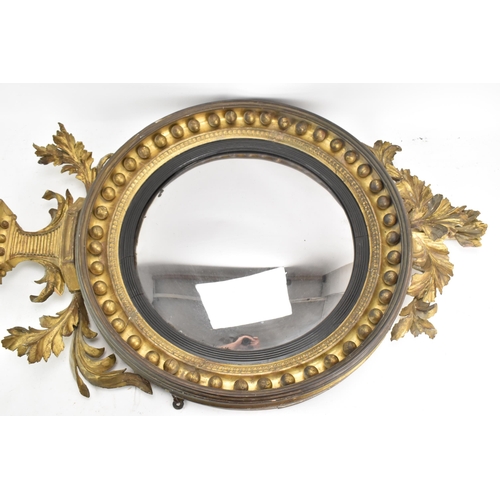 141 - A Regency wall mirror, having a convex plate in a gilt moulded and carved giltwood frame with a ball... 