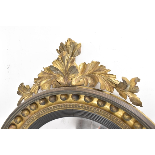 141 - A Regency wall mirror, having a convex plate in a gilt moulded and carved giltwood frame with a ball... 