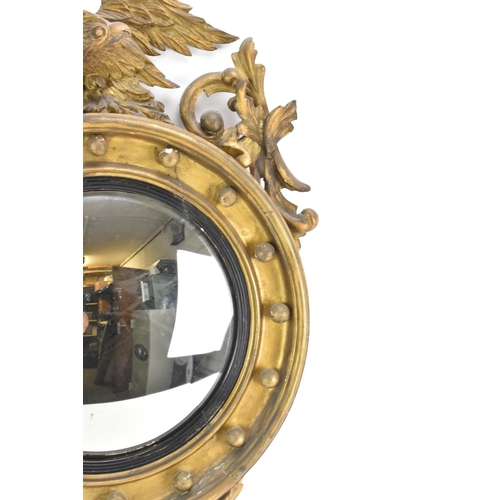 142 - A Regency wall mirror, having a convex plate in a gilt moulded and carved giltwood frame with a ball... 