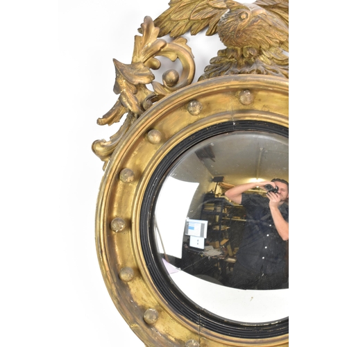 142 - A Regency wall mirror, having a convex plate in a gilt moulded and carved giltwood frame with a ball... 