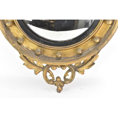 142 - A Regency wall mirror, having a convex plate in a gilt moulded and carved giltwood frame with a ball... 