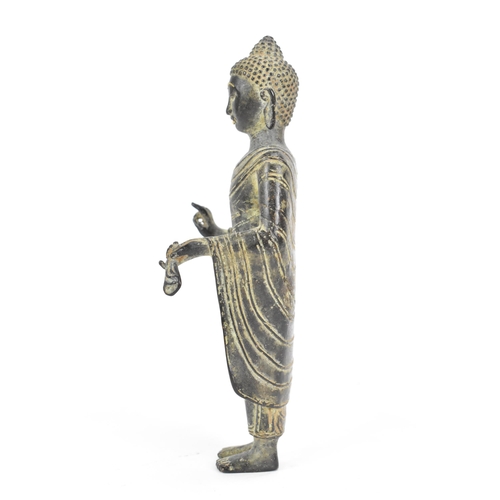 28 - A Cambodian Khmer bronze figure of a Buddha, in a standing Mudra position, wearing elegant monastic ... 