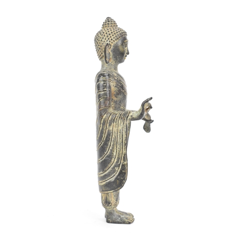 28 - A Cambodian Khmer bronze figure of a Buddha, in a standing Mudra position, wearing elegant monastic ... 