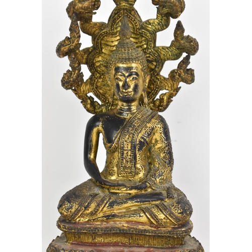 48 - A 19th century Thai gilt bronze Buddha, Cast seated in meditation on a coiled snake, his hands held ... 