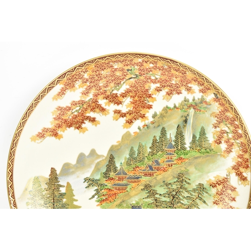 54 - A Japanese Meiji period satsuma dish, by Koshida, the interior decorated with a river scene, buildin... 