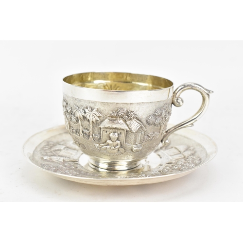 68 - An early 20th century Indian white metal cup and saucer, each embossed with a band depicting a conti... 