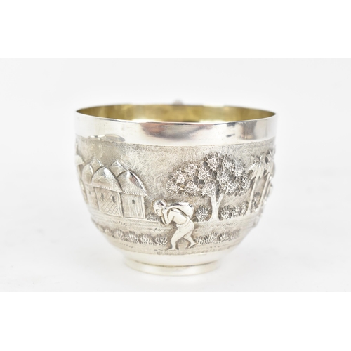 68 - An early 20th century Indian white metal cup and saucer, each embossed with a band depicting a conti... 