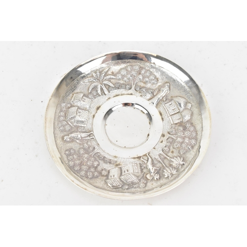 68 - An early 20th century Indian white metal cup and saucer, each embossed with a band depicting a conti... 