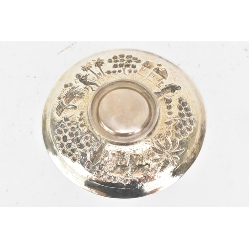 68 - An early 20th century Indian white metal cup and saucer, each embossed with a band depicting a conti... 