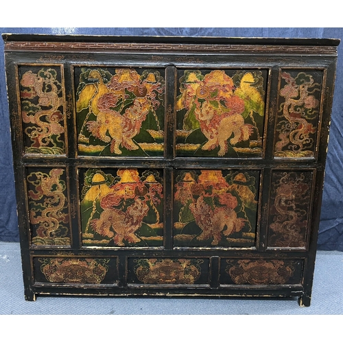 76 - A 19th century Tibetan cabinet, lacquered and polychrome painted with panels depicting foo dogs and ... 