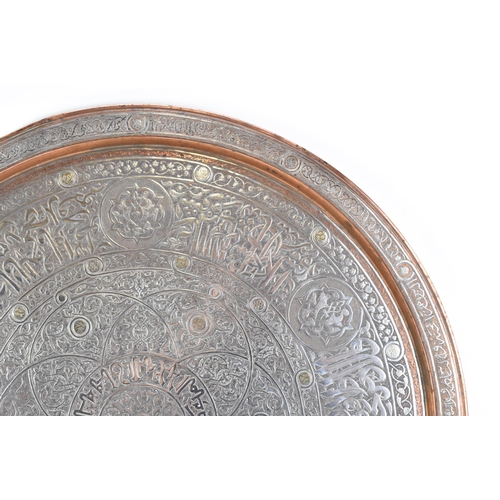 82 - An Iranian Qajar large circular copper tray, circa 1900, with white metal overlaid, decorated with o... 