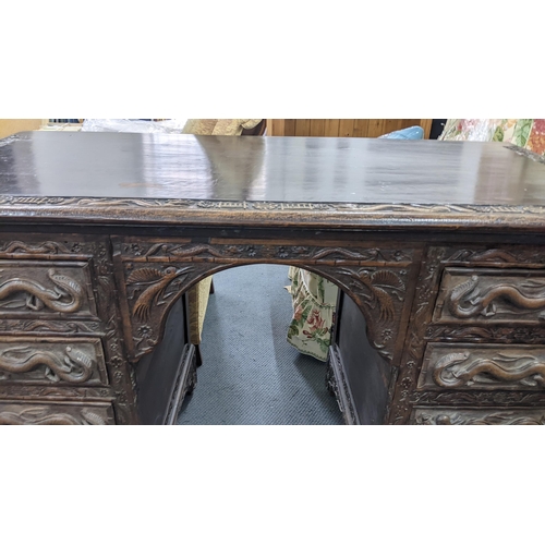 83 - An early 20th century Chinese export padouk wood twin pedestal desk, relief carved decorated with dr... 