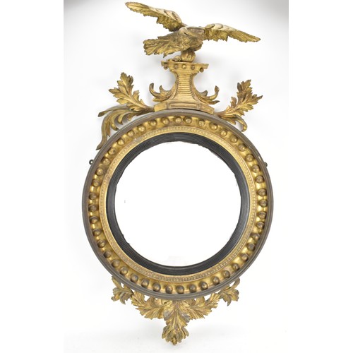 141 - A Regency wall mirror, having a convex plate in a gilt moulded and carved giltwood frame with a ball... 