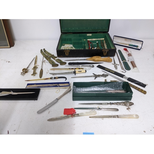 265 - A collection of vintage paper knives, small ornamental daggers and a silver plate meat skewer, conta... 