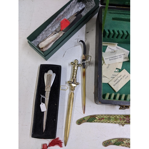 265 - A collection of vintage paper knives, small ornamental daggers and a silver plate meat skewer, conta... 