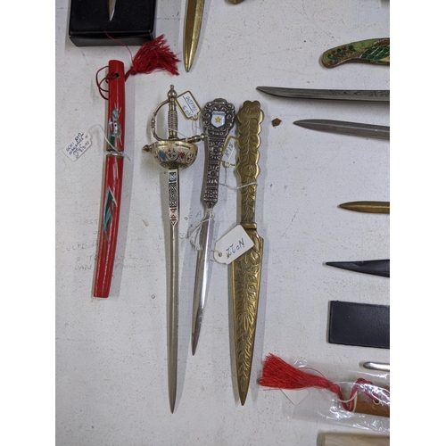 265 - A collection of vintage paper knives, small ornamental daggers and a silver plate meat skewer, conta... 