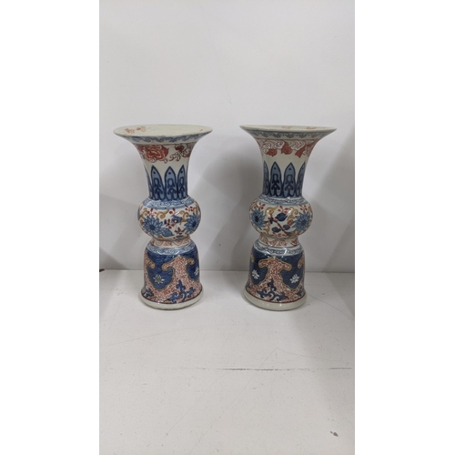 299 - A pair of Chinese 20th century vases of Gu form decorated in blue and white with red painted scrolle... 