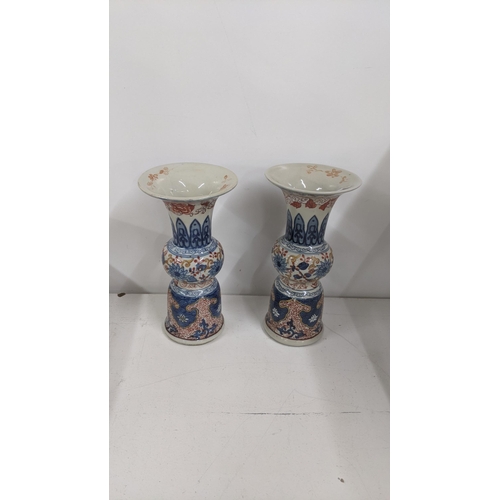 299 - A pair of Chinese 20th century vases of Gu form decorated in blue and white with red painted scrolle... 