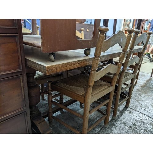 77 - An oak trestle end dining table, rectangular top supported on turned columns, united by square stret... 