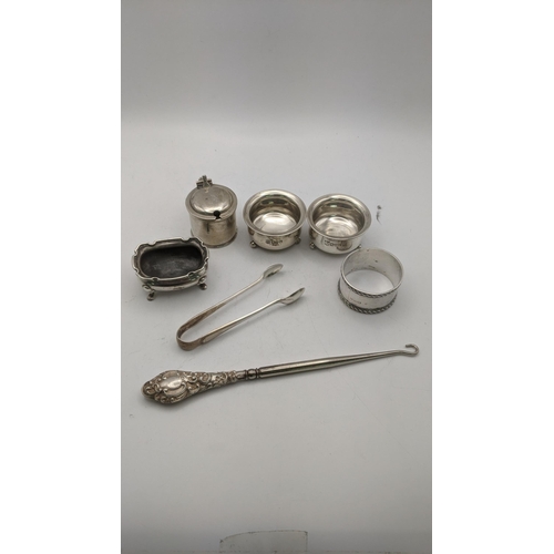 131 - Silver to include condiment pots, sugar tongs, a napkin ring and silver handled button hook, total w... 