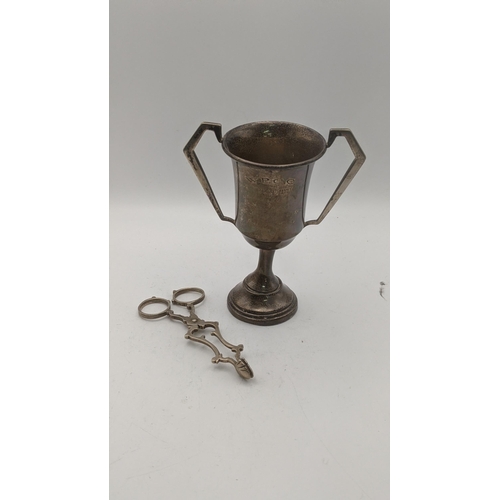 154 - Silver to include a twin handled cup, hallmarked London 1937, together with a pair sugar tongs, tota... 