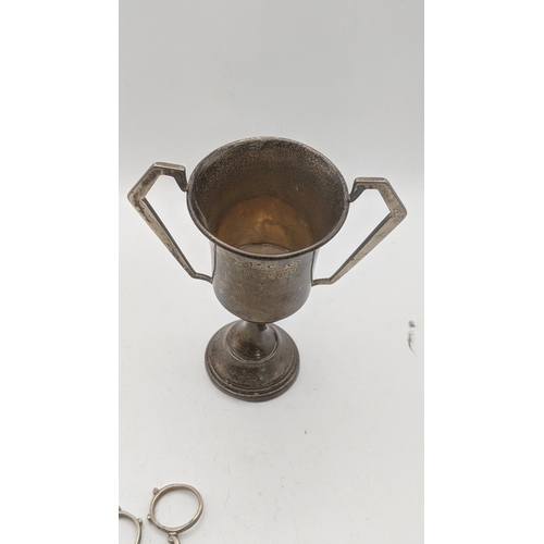 154 - Silver to include a twin handled cup, hallmarked London 1937, together with a pair sugar tongs, tota... 