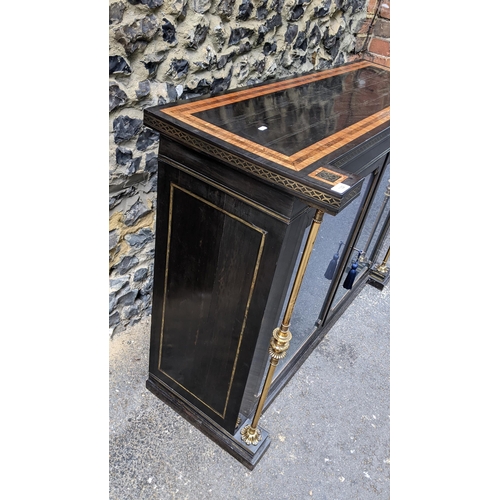 132 - A Regency ebonised chiffonier having two glazed doors, fitted with a loose shelf, flanked by two bra... 