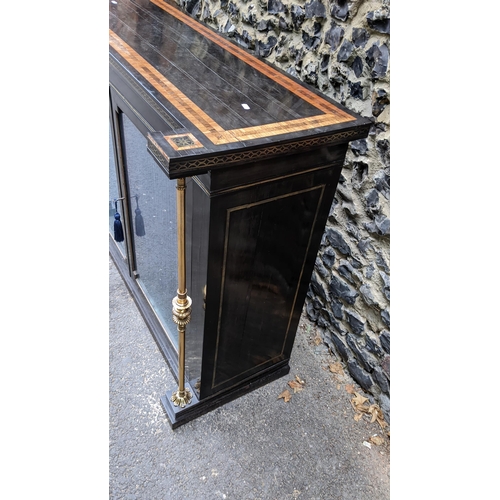 132 - A Regency ebonised chiffonier having two glazed doors, fitted with a loose shelf, flanked by two bra... 