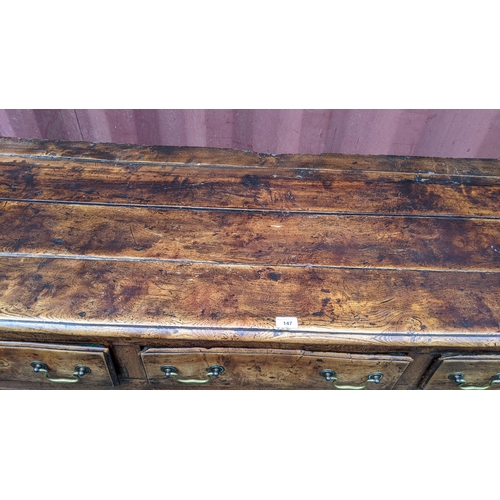 147 - An 18th century vernacular fruitwood sideboard, having three central drawers flanked by two further ... 