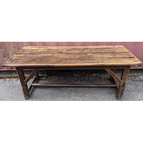 148 - An 18th century vernacular oak dining table, having a plank constructed top, four chamfered legs uni... 