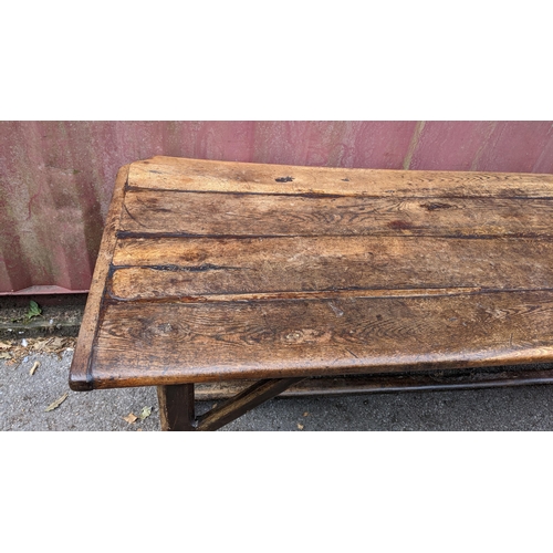 148 - An 18th century vernacular oak dining table, having a plank constructed top, four chamfered legs uni... 