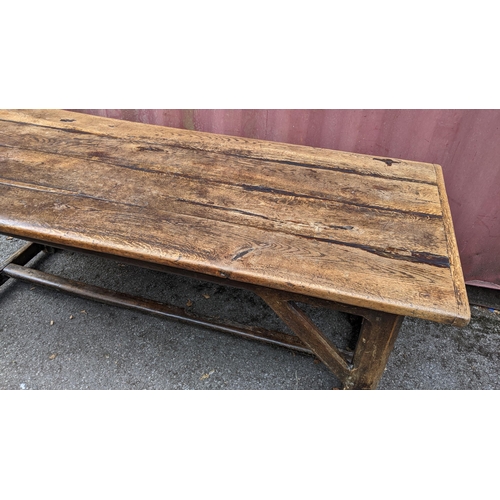 148 - An 18th century vernacular oak dining table, having a plank constructed top, four chamfered legs uni... 